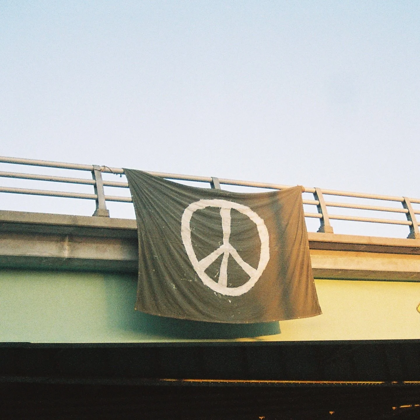 A black flag with a white peace symbol hanging over a balcony railing.