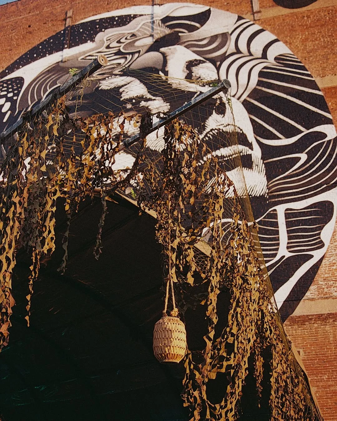 Indoor decor with a black and white mural of a skull, a black canopy with gold leaves, and a hanging lantern.