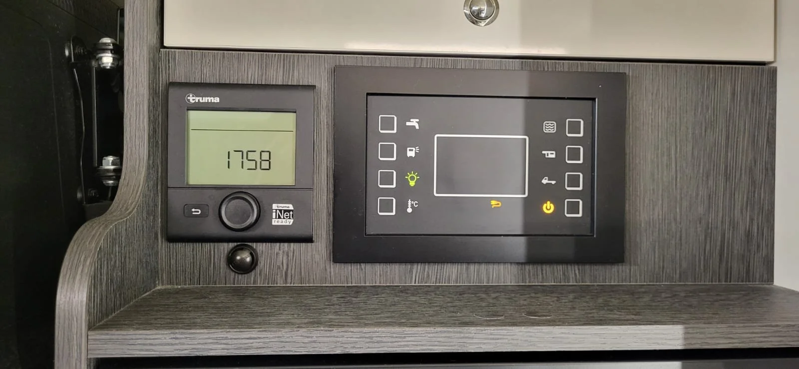 Digitale controlepanelen en display van een verwarmingssysteem of apparaat, met een wandklok die 17:58 toont.
