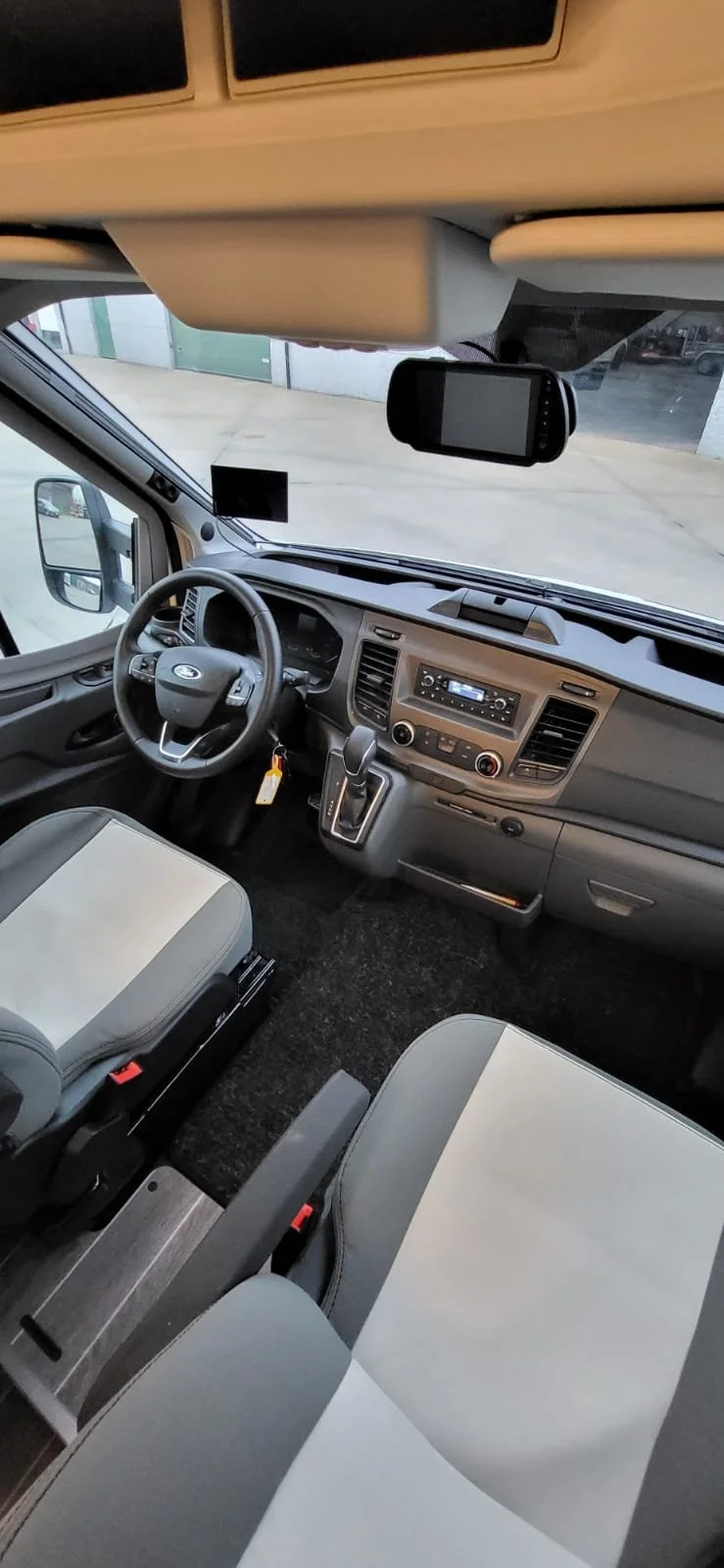 Interieur van een vrachtwagenchauffeurscabine met bestuurdersstoel, stuur en dashboard, blik op de weg buiten.