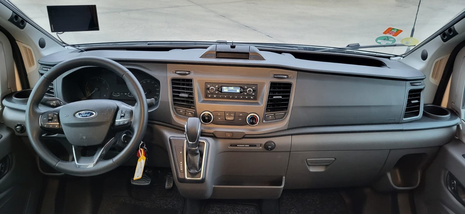 Interieur van een rode Ford vrachtwagen met stuur, dashboard, radio, en versnellingspook.