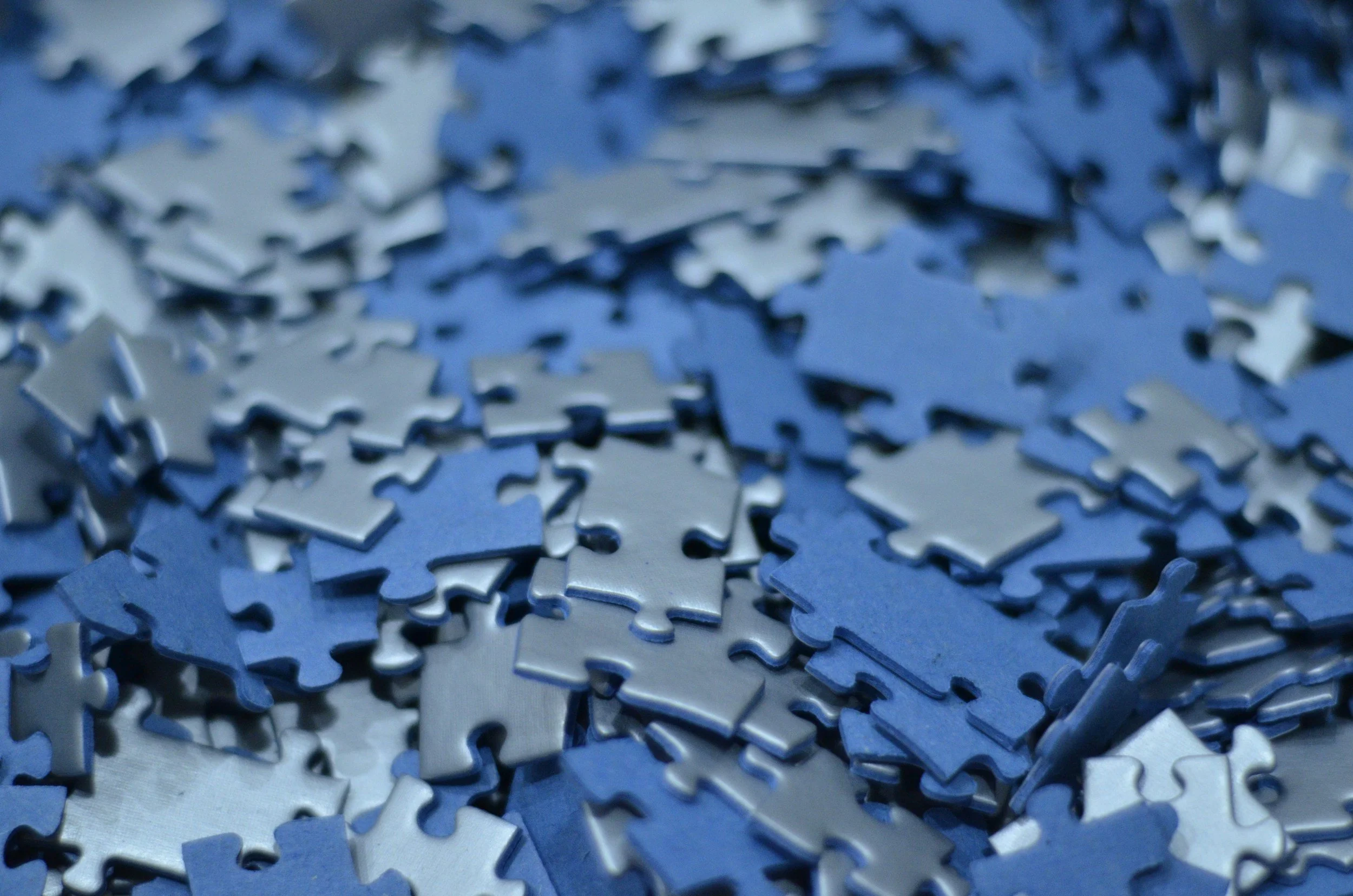 A close-up of scattered blue and silver jigsaw puzzle pieces.