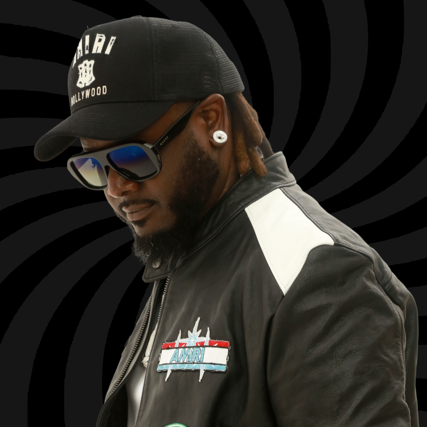 A man wearing a black baseball cap with white logo, sunglasses, a leather jacket with a NASA patch, and earrings. The background is black with swirling gray lines.