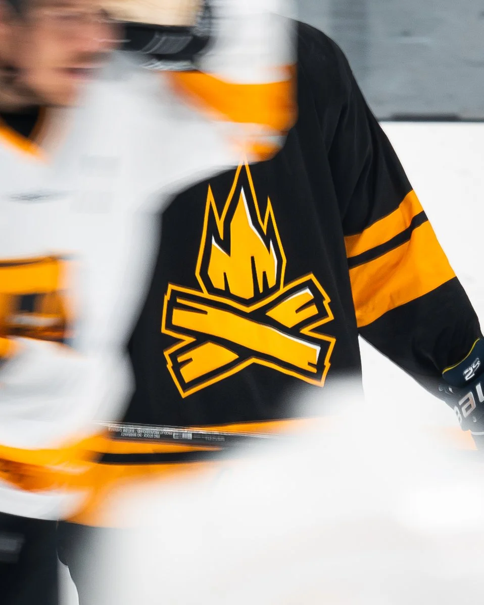 Close-up of a hockey player wearing a black and orange jersey with a logo of an axe embedded in flames.