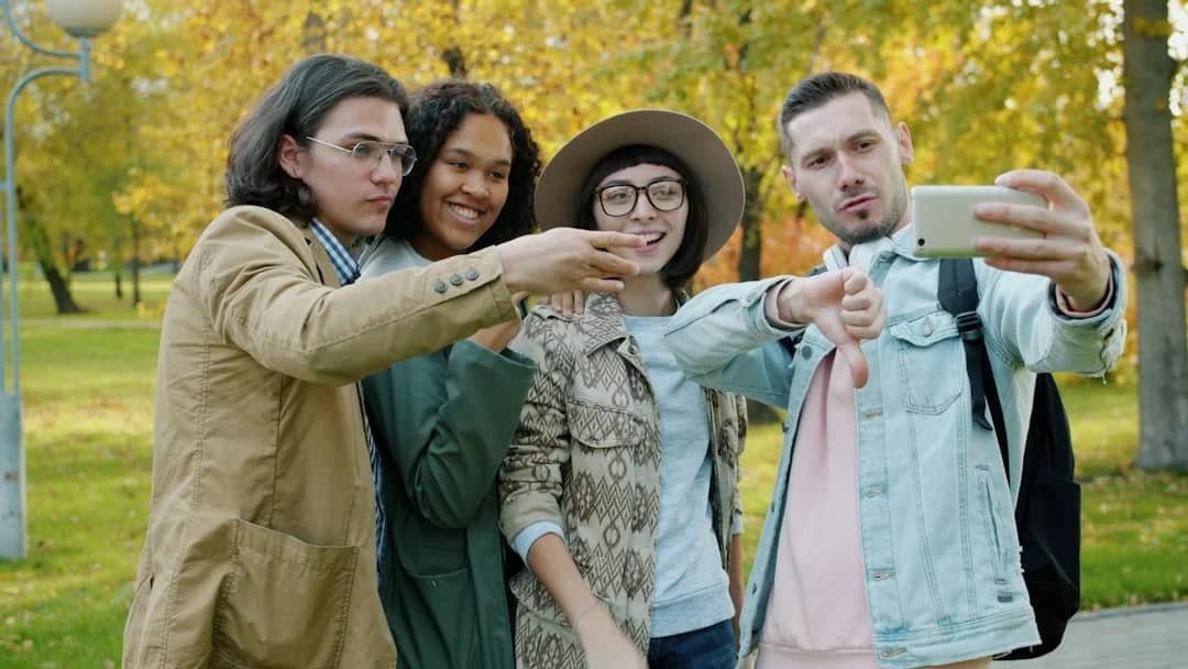 Diverse group of friends laughing and taking a selfie outdoors representing restored connection and joy after trauma healing