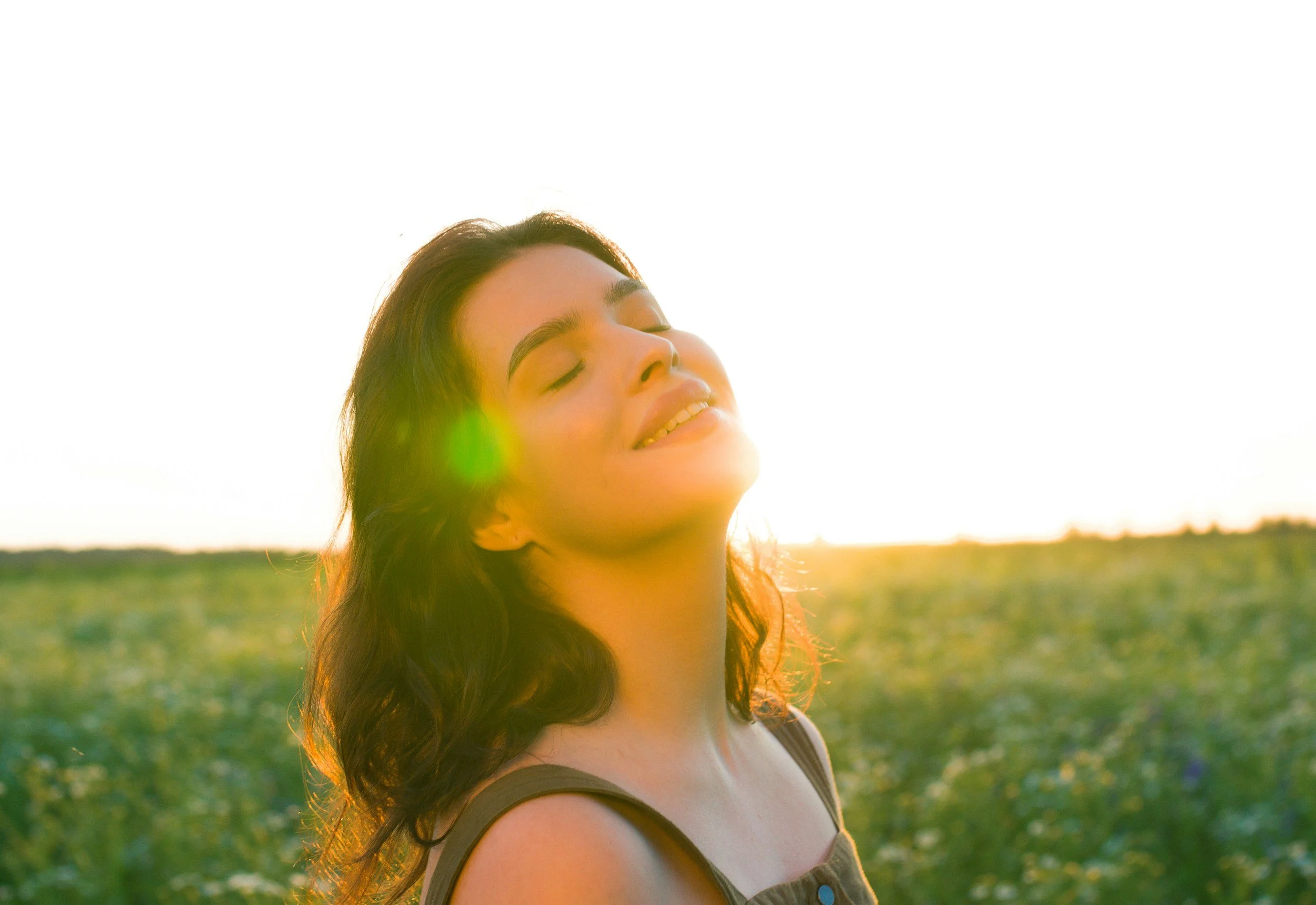Woman with eyes closed smiling in golden sunlight representing peace and emotional freedom through trauma therapy in Phoenix AZ