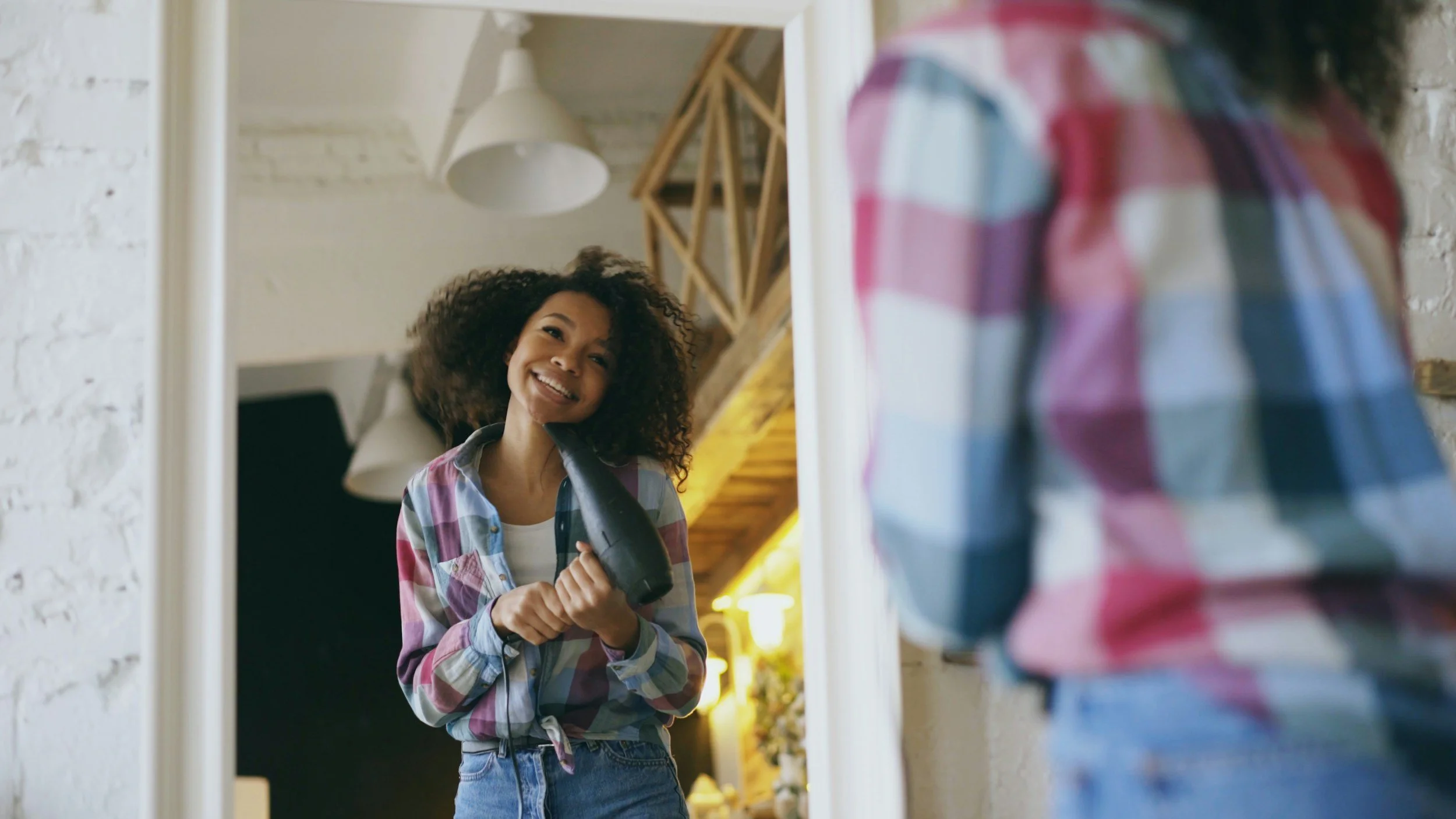Woman smiling at her reflection in a mirror representing self-acceptance and renewed identity through therapy for women