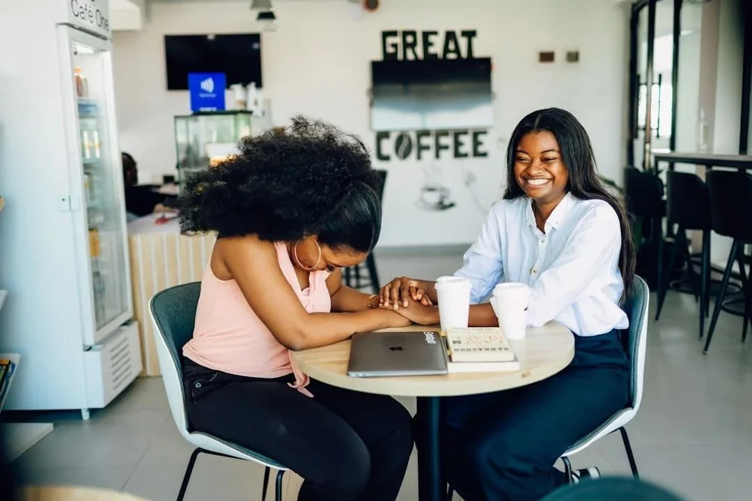 Two women sharing a joyful moment together at a coffee shop representing connection and healing through therapy in Phoenix AZ