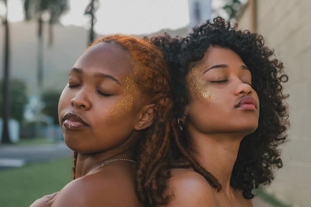 Two Black women leaning back-to-back with eyes closed, representing connection, mindfulness, and emotional healing through trauma therapy in Phoenix, AZ