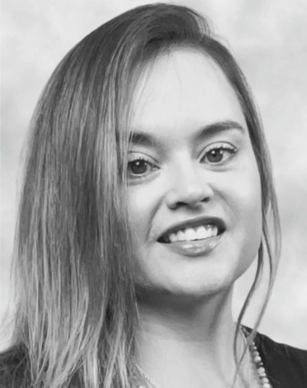 Close-up portrait of a woman with long hair, smiling, in black and white.