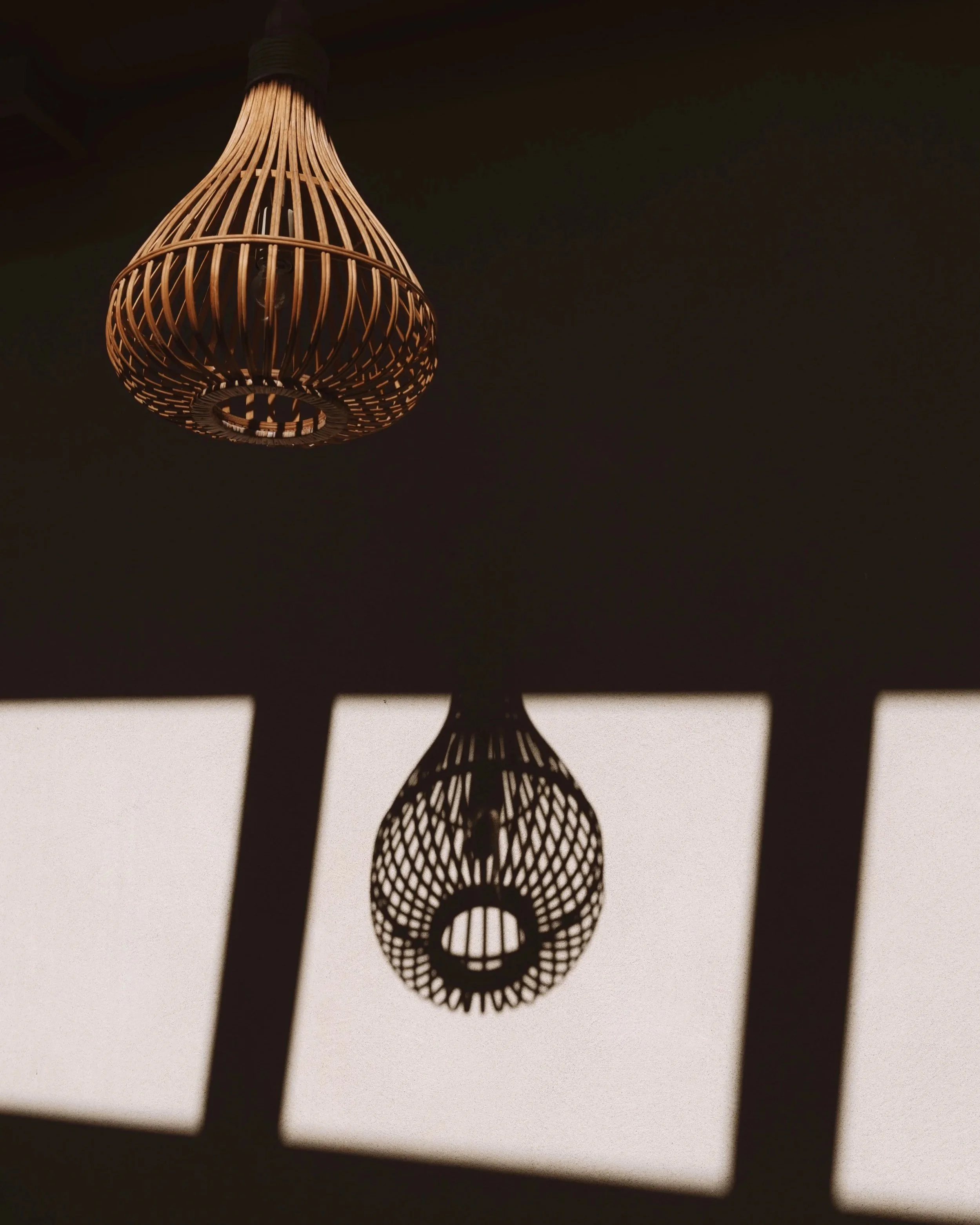 Suspension en bois en forme de cage avec ombre de la lumière du plafond sur le mur.
