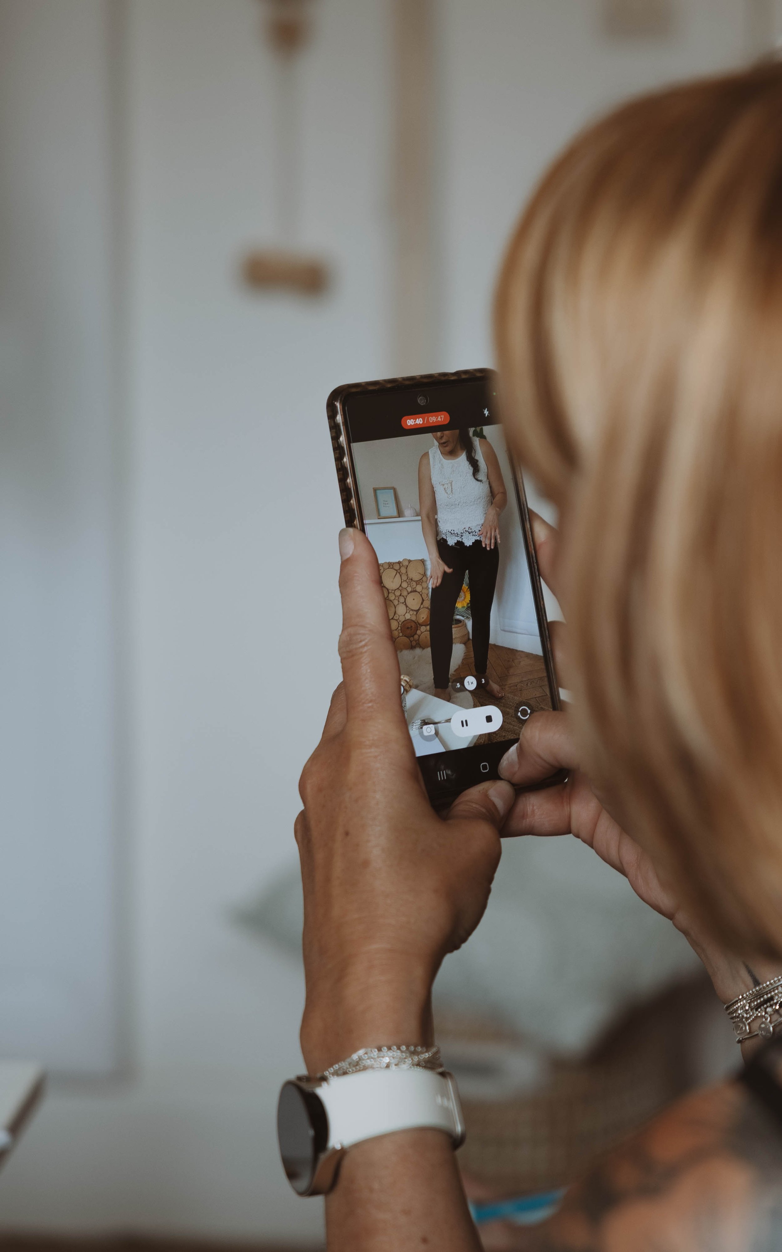 Une femme prend une photo d'une autre femme avec un smartphone dans une pièce intérieure.