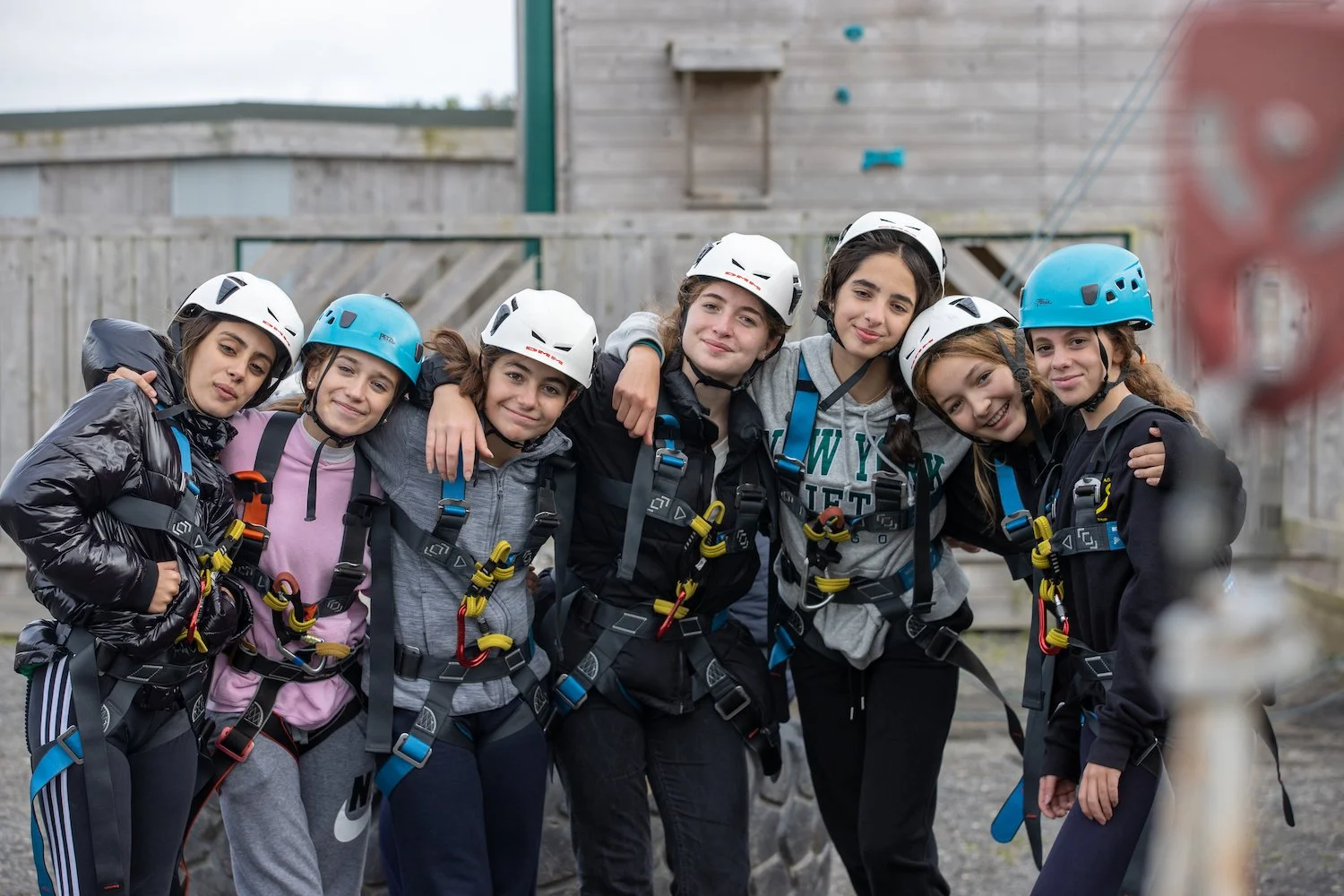 Grupo de siete adolescentes con casco y arnes de escalada en un área al aire libre