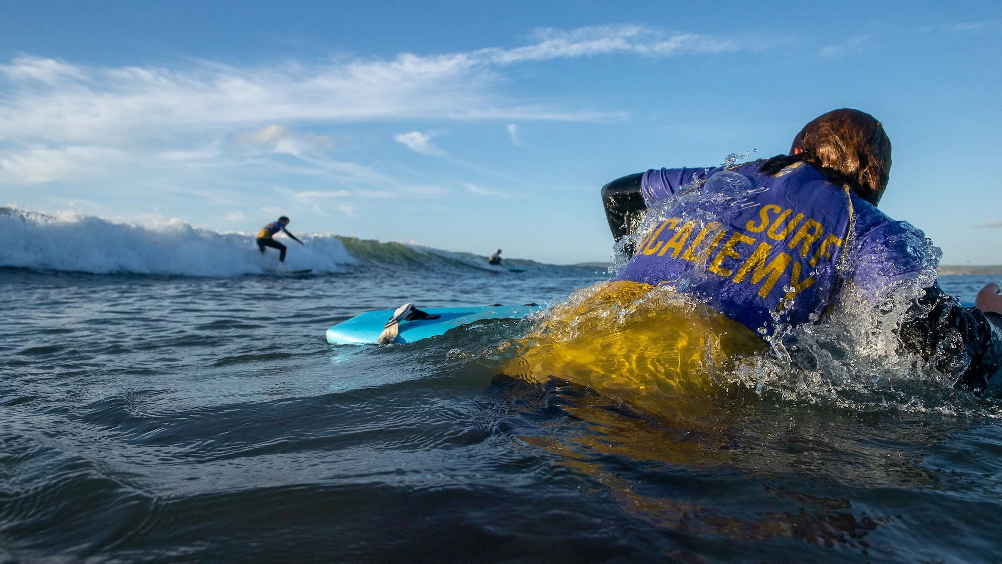 Salvavidas observando surfistas en el mar bajo cielo azul.