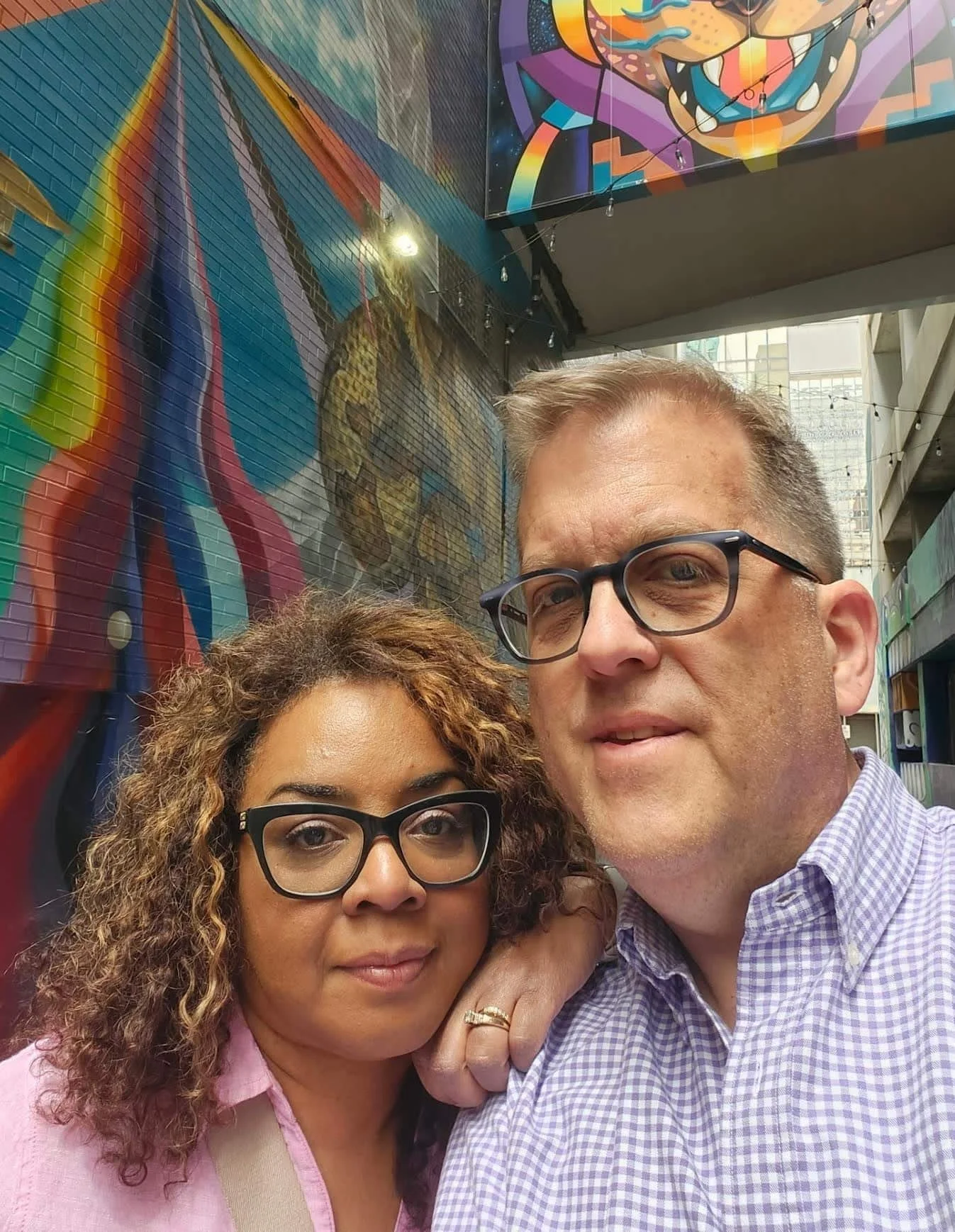 Newburgh Mercantile owners, Eric and Jacqui Jarmann, in front of colorful, abstract murals on walls.