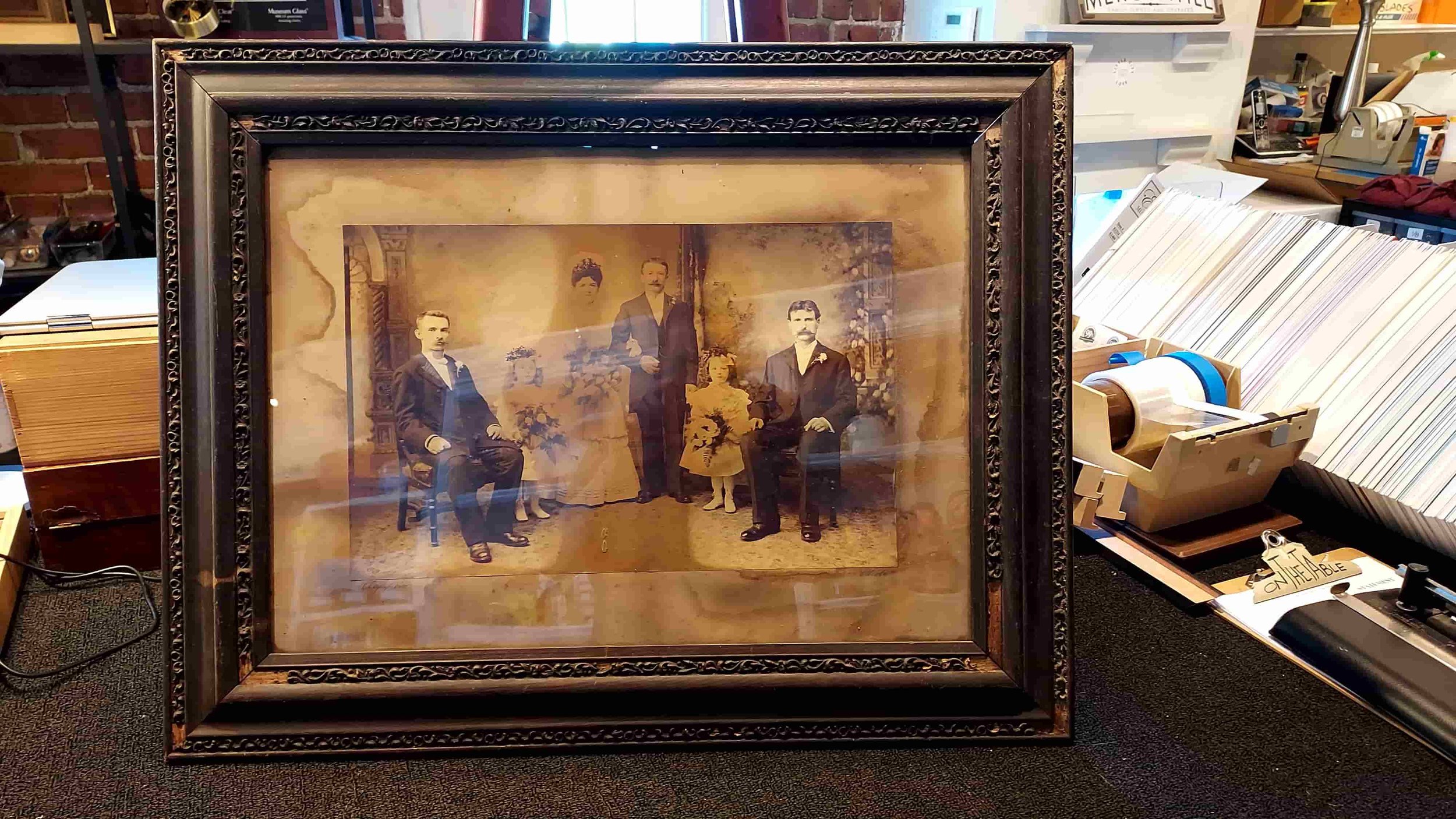 Antique, severely water-damaged framed family photograph, showing a blurred group of six people.