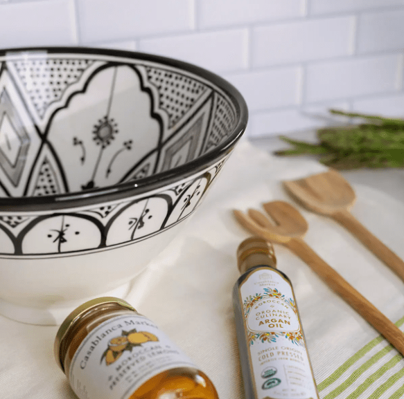Close-up of eclectic home decor display, including an ornate gold frame, a modern wood frame with botanical art, and a shell-shaped Casablanca dish.
