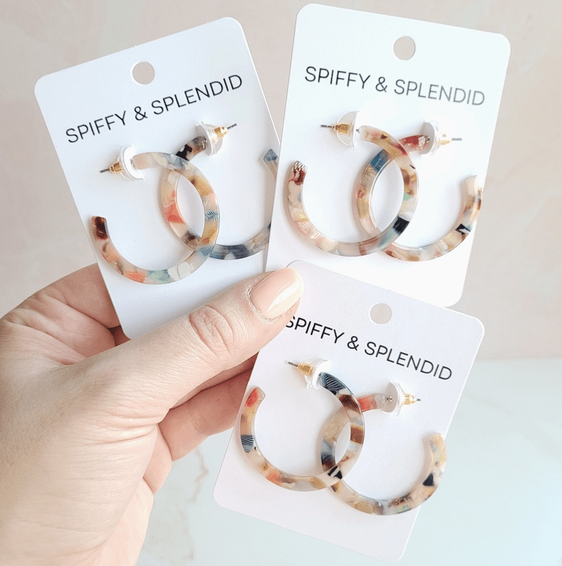 Spiffy & Splendid Multicolor Camy Hoops: A hand holds three pairs of small, tortoiseshell-style acrylic hoop earrings on white product cards.