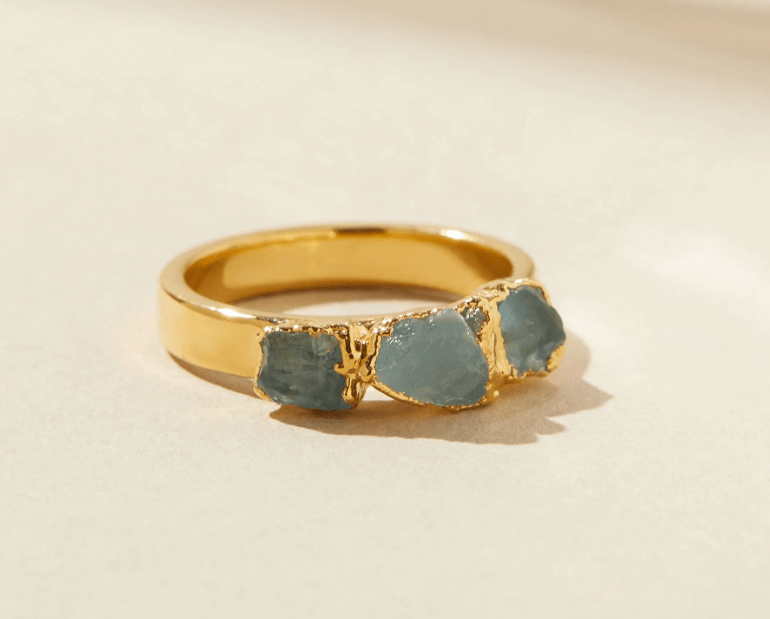 Dani Barbe Aquamarine Stacking Ring, a gold band set with three raw, pale blue aquamarine gemstones.