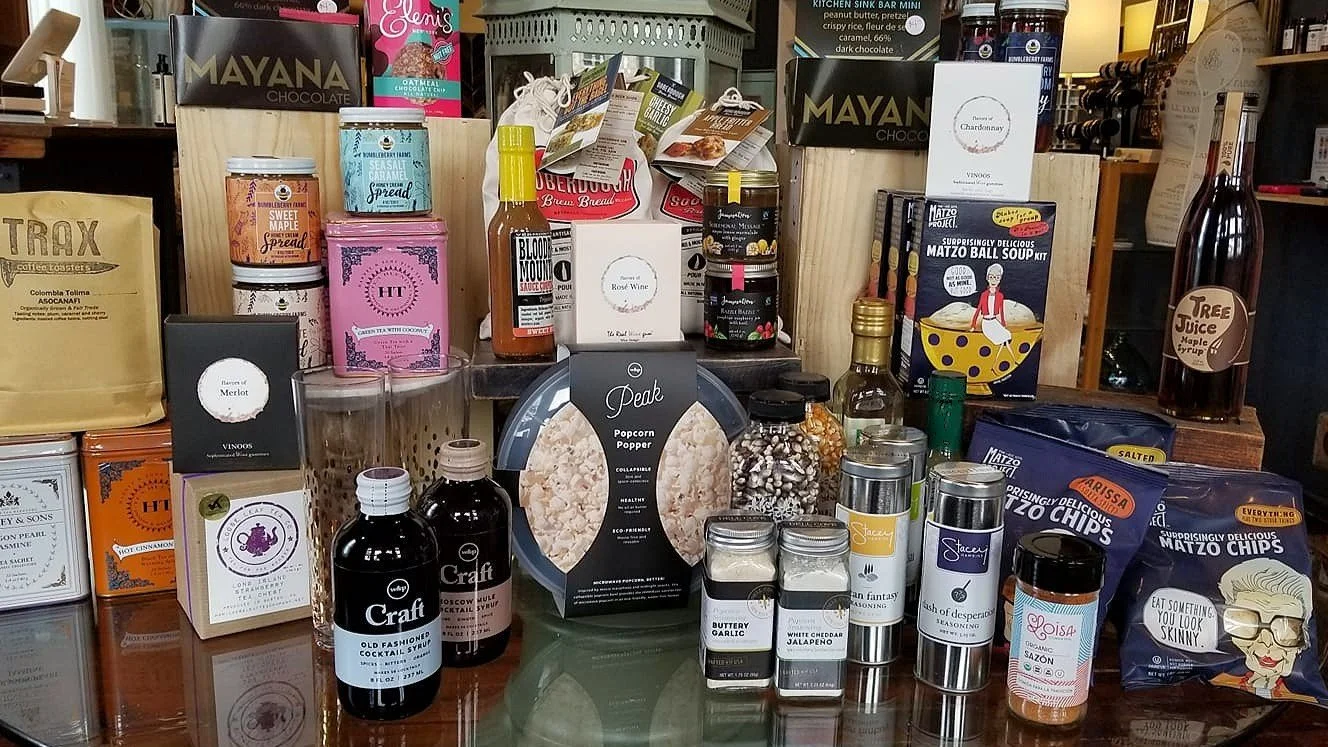 Curated, gourmet food products display at Newburgh Mercantile with cocktail syrup, popcorn, seasonings, chocolate, and spread.