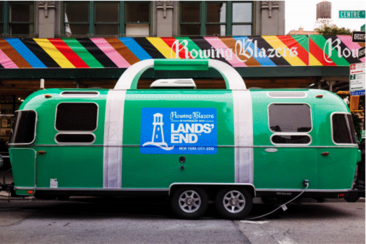 A green mobile food truck with white trim features a blue sign for the Howling Blazers Lands' End event in Times Square, NYC.