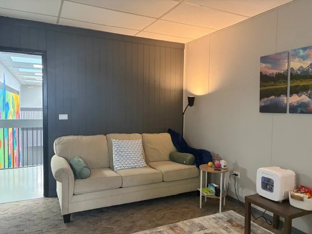 Living room with beige sofa, pillows, a side table, wall art, and a white humidifier.