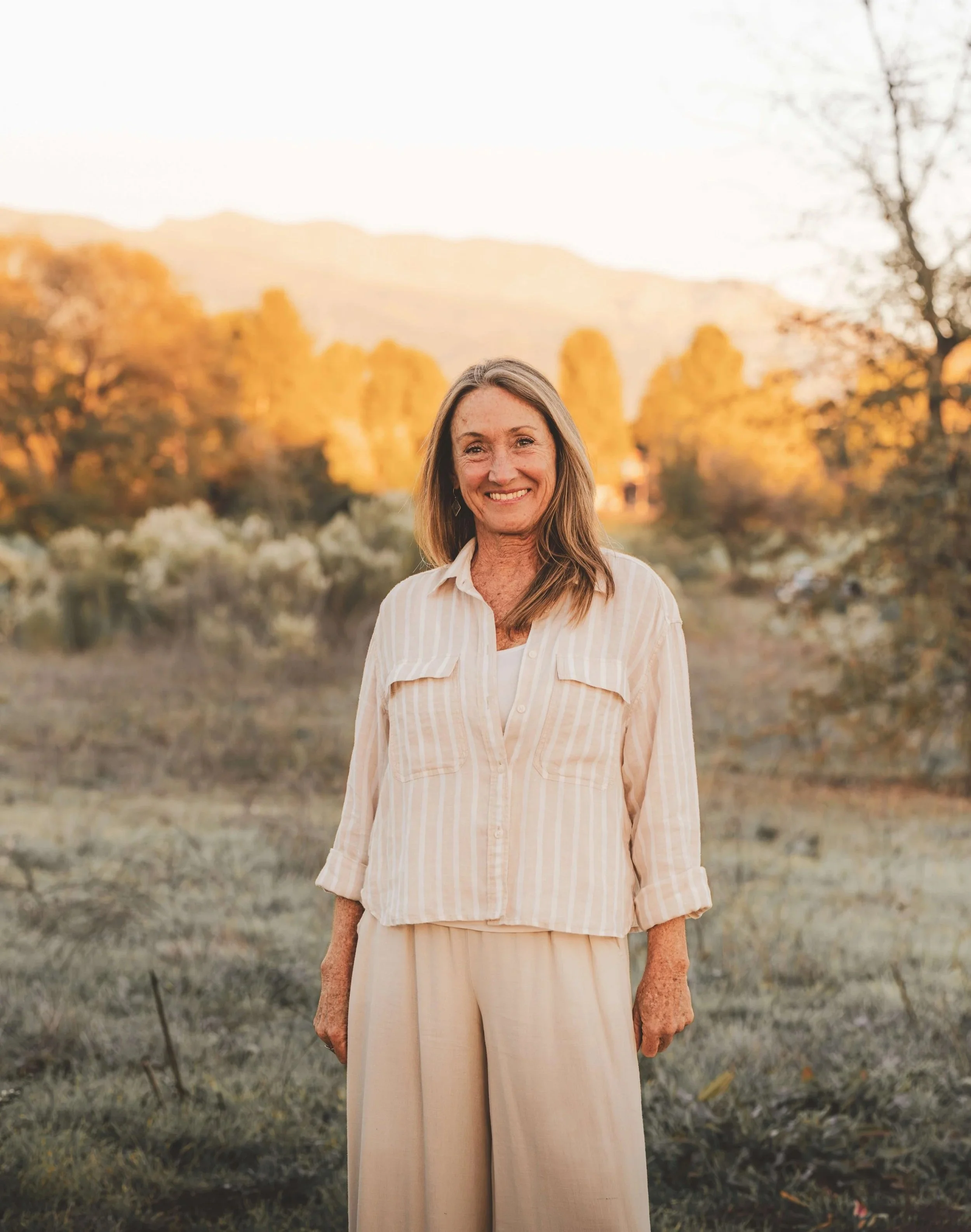 Amyris Wilson smiling outdoors in Ojai, California during sunset with a scenic background of trees and the Topa Topa mountains.