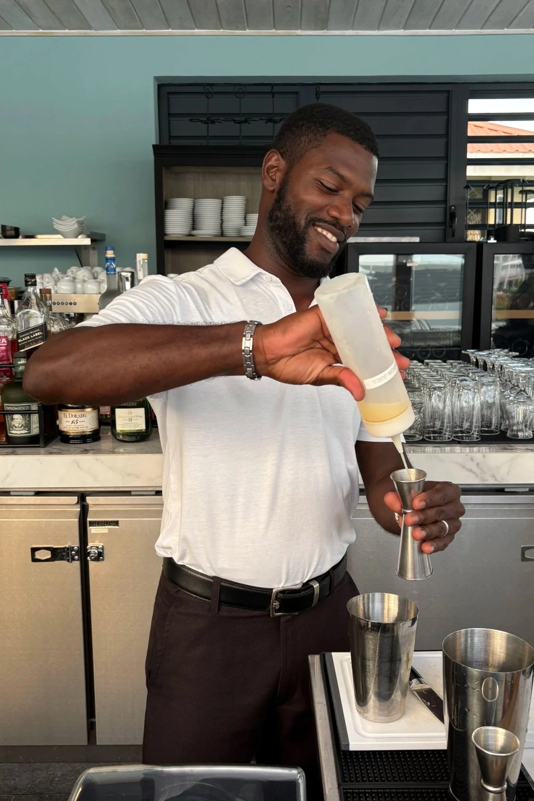 A bartender smiling while pouring a cocktail at The Harvest and Table Restaurant.