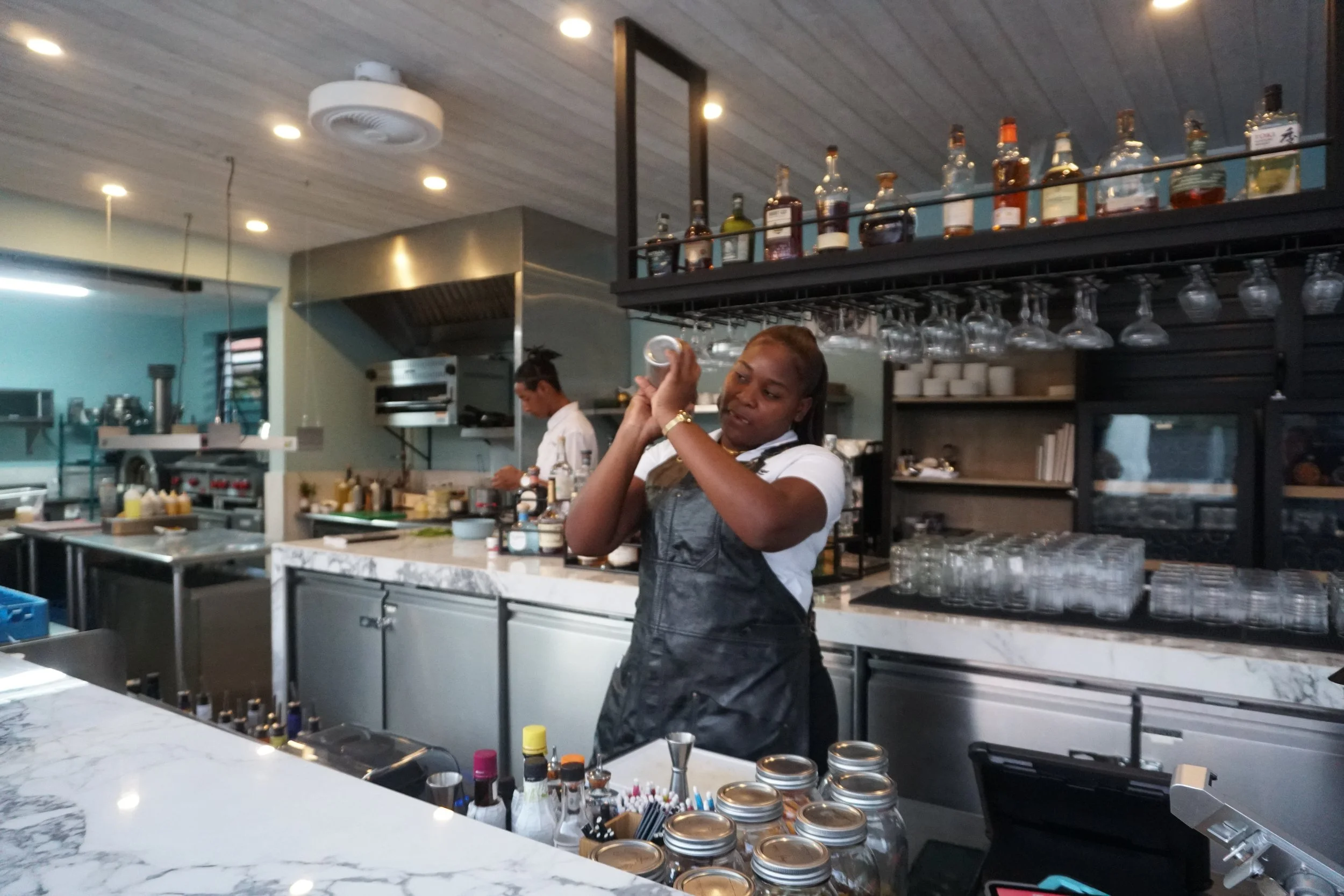 A bartender shaking a cocktail shaker behind the bar at The Harvest and Table Restaurant. 
