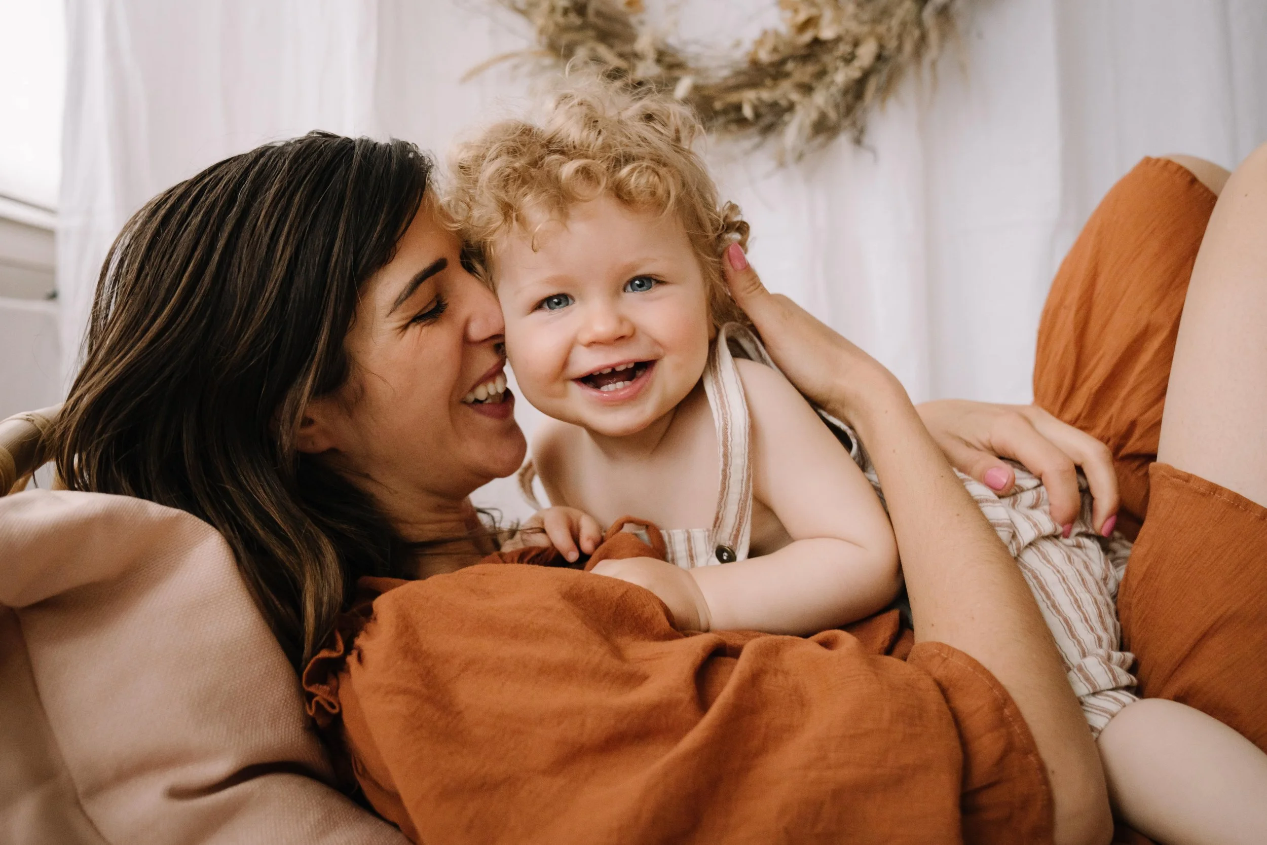 Mother and young child playing and smiling together at home.