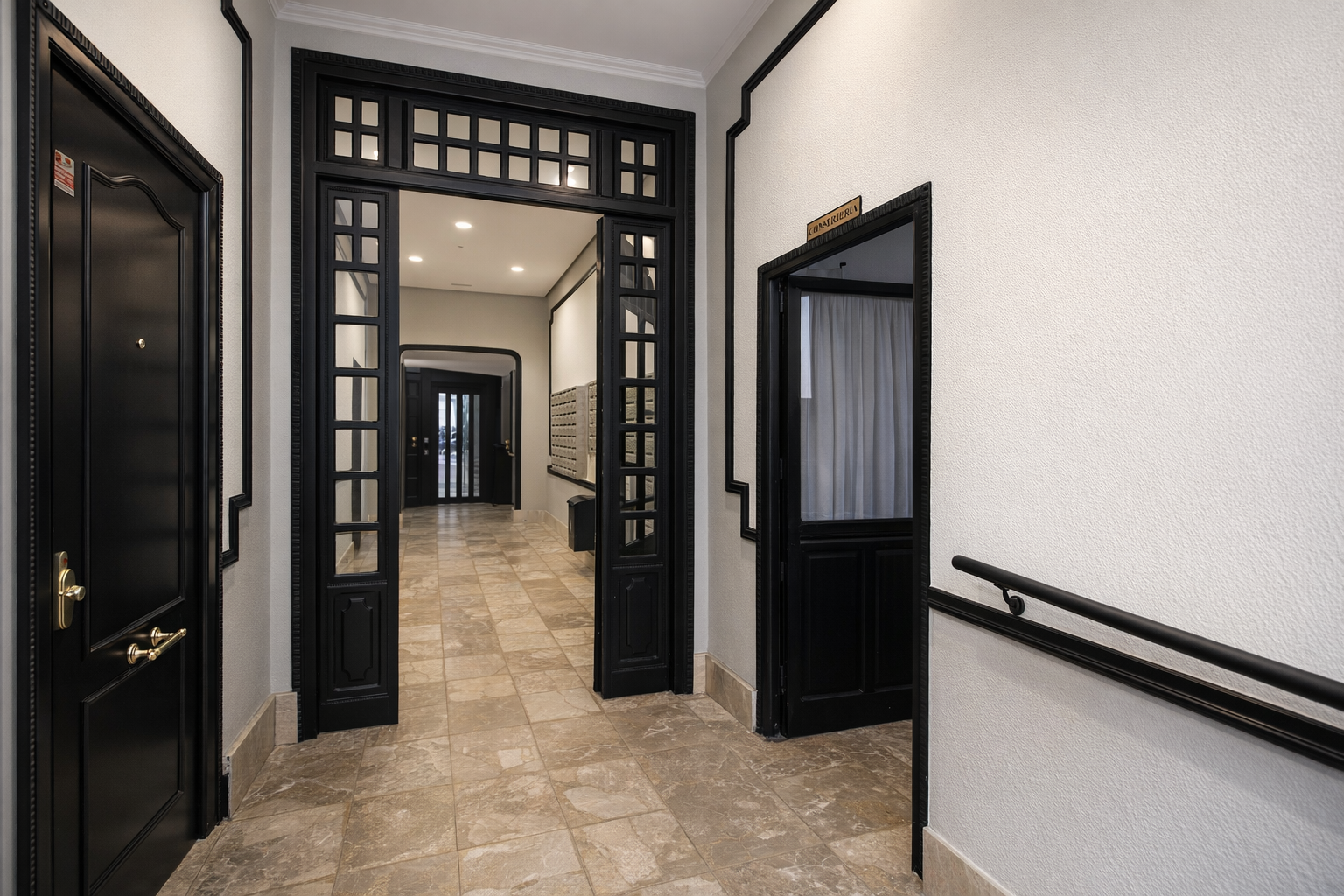 Vestíbulo de entrada con paredes blancas, molduras negras y suelo de baldosas beige con vetas.