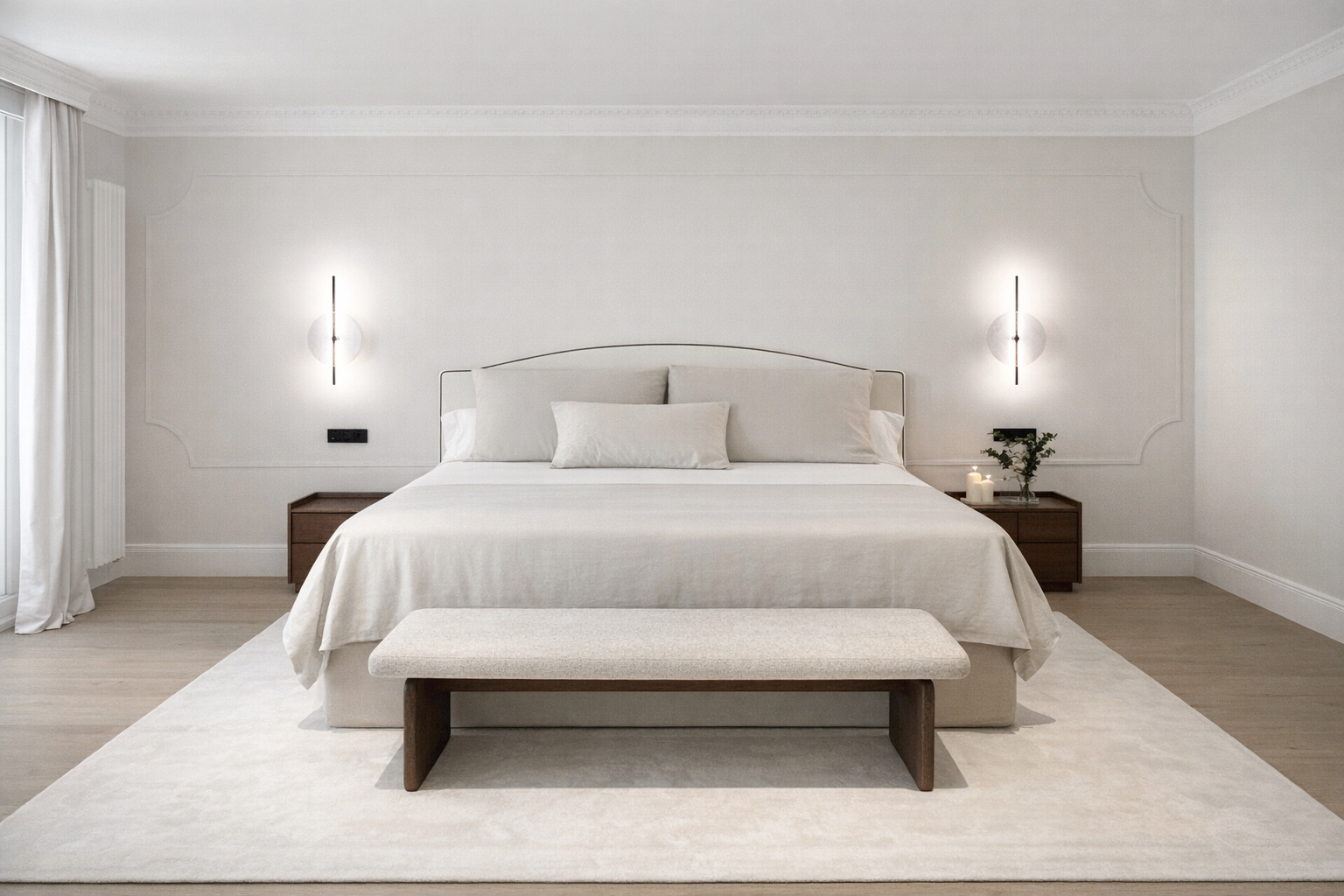 Dormitorio minimalista con cama grande, ropa de cama blanca, dos noche en madera, dos lámparas de pared y cojines decorativos, en un ambiente luminoso y elegante.