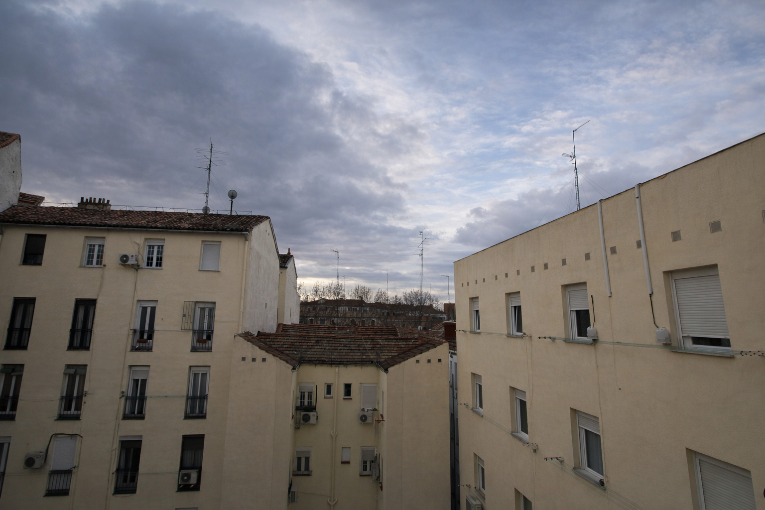 Vista de edificios residenciales con ventanas y antenas de televisión en un cielo nublado