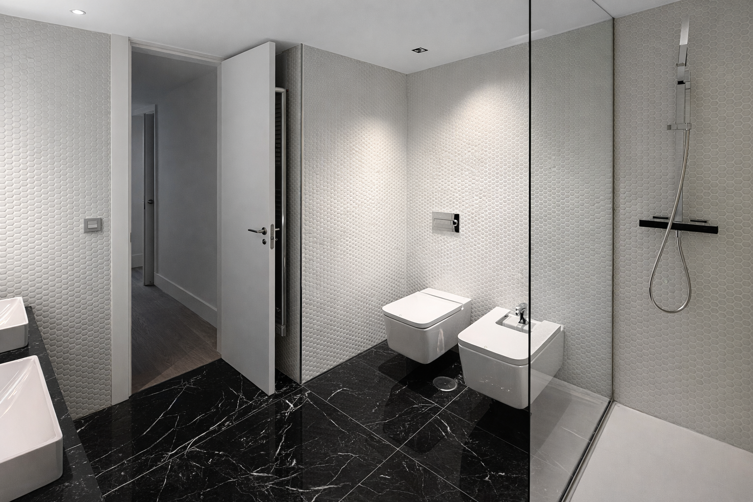 Cuarto de baño moderno con paredes de textura en color blanco, piso de mármol negro, sanitarios blancos, área de ducha con mampara de vidrio y accesorios de ducha ajustados a la pared.