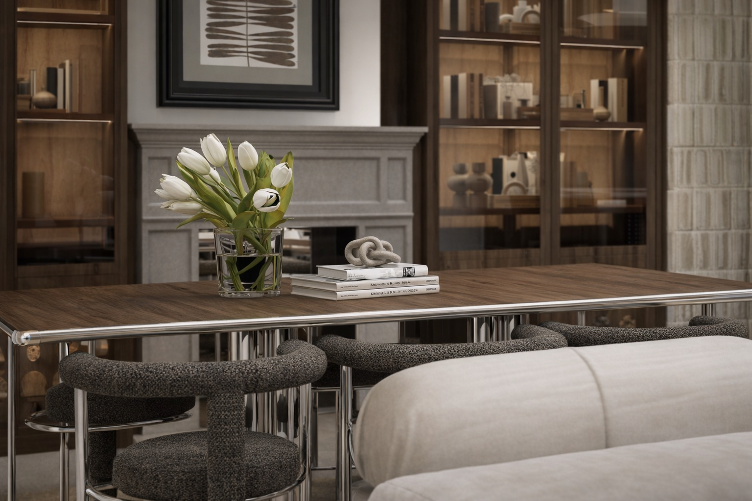 Mesa de madera con un florero de tulipanes blancos, algunos libros apilados y una escultura decorativa en la sala de un hogar, con gabinetes de madera en el fondo.