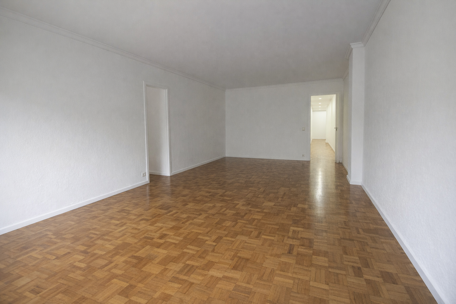 Sala vacía con paredes blancas y suelo de parquet de madera