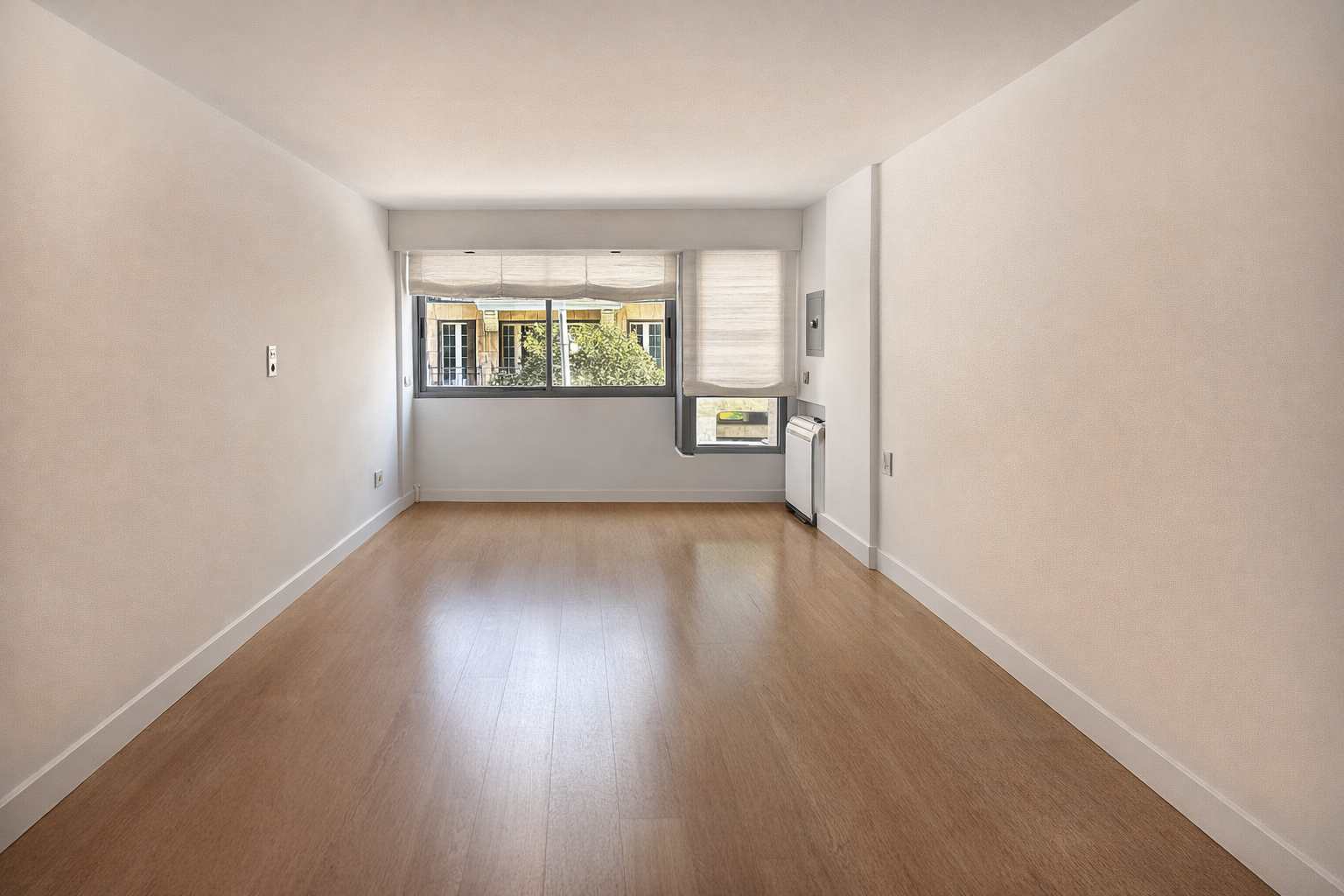 Habitación vacía con paredes blancas, ventanas grandes con cortinas blancas, y suelo de madera clara.