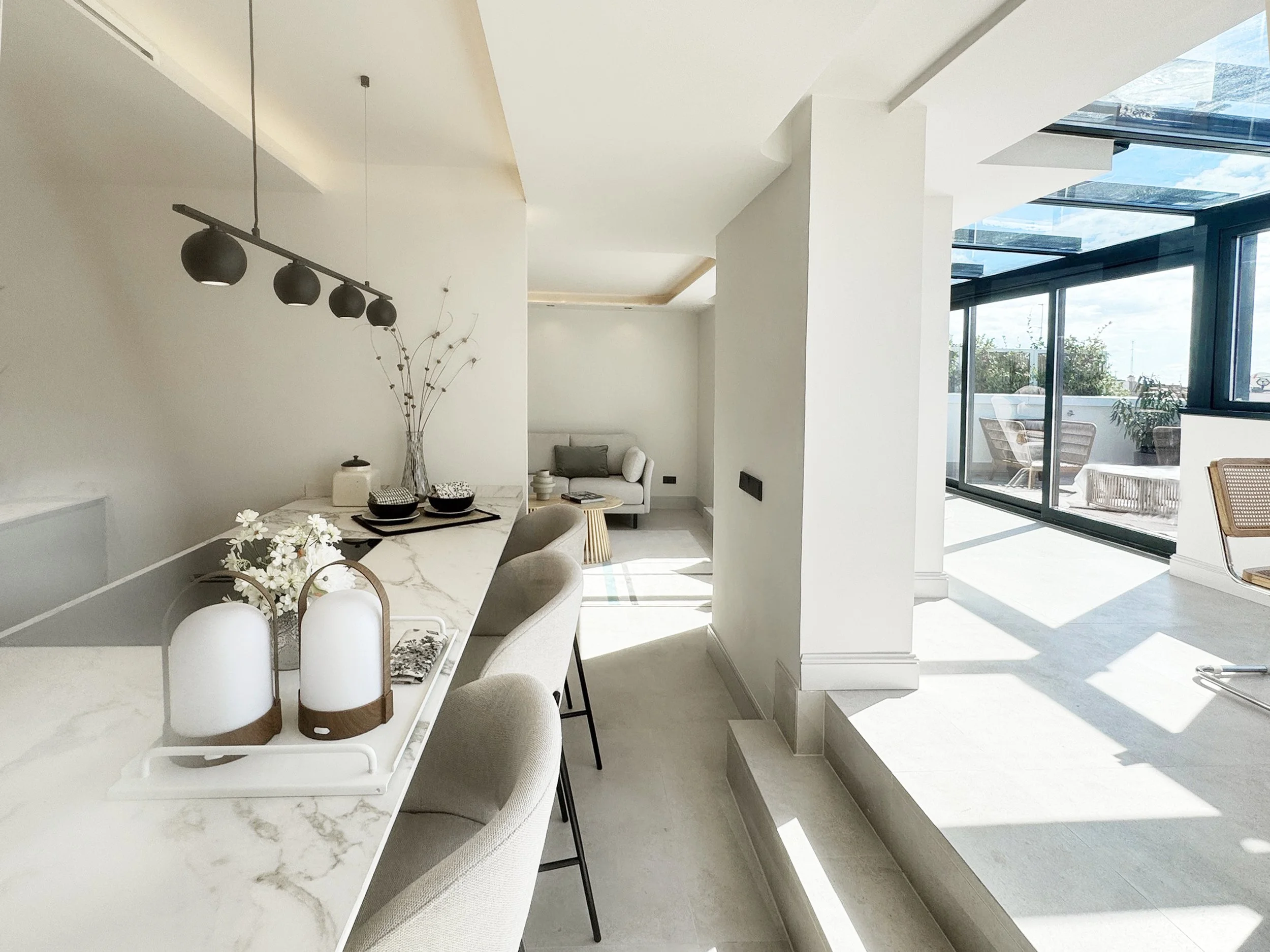 Interior de una sala de estar y comedor con decoraciones en tonos claros y mucha luz natural