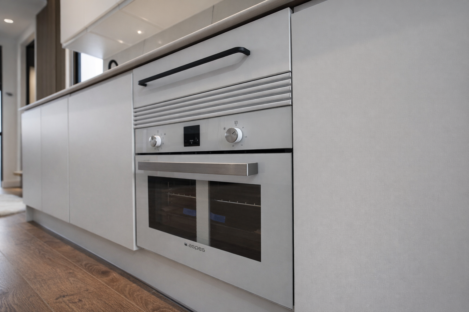 Cocina moderna con horno empotrado y gabinetes blancos en una cocina contemporánea.