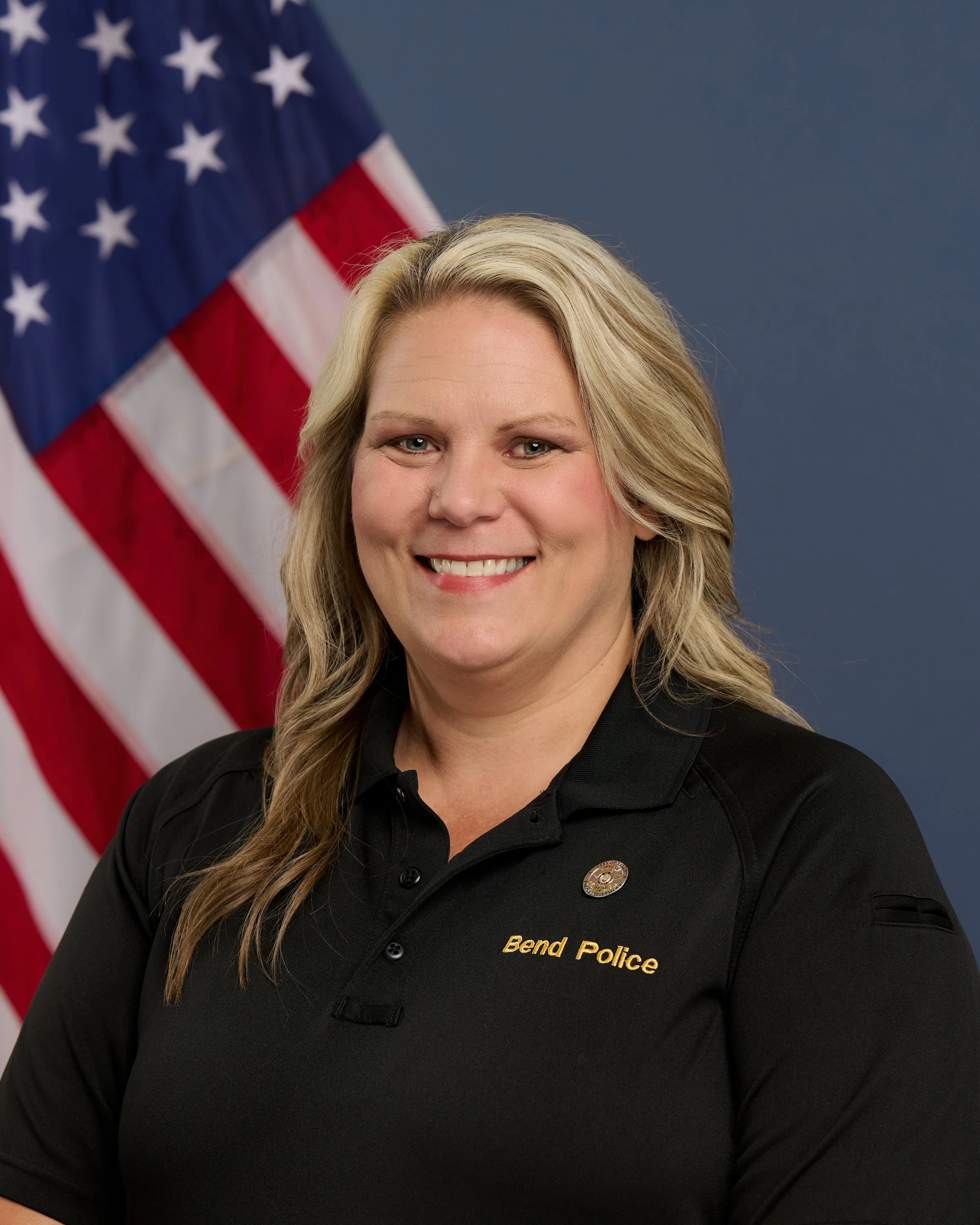 woman in black polo shirt with American flag in background Kara Hill