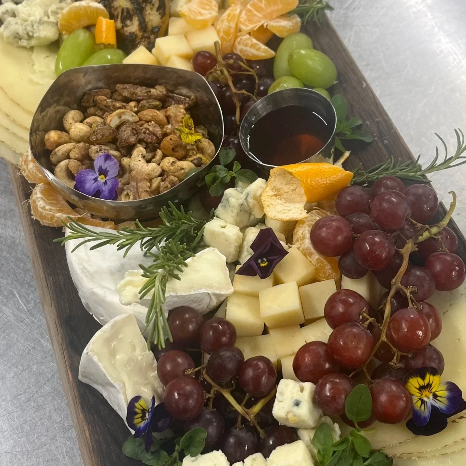 Cheese platter charcuterie board with grapes, nuts, and edible flowers
