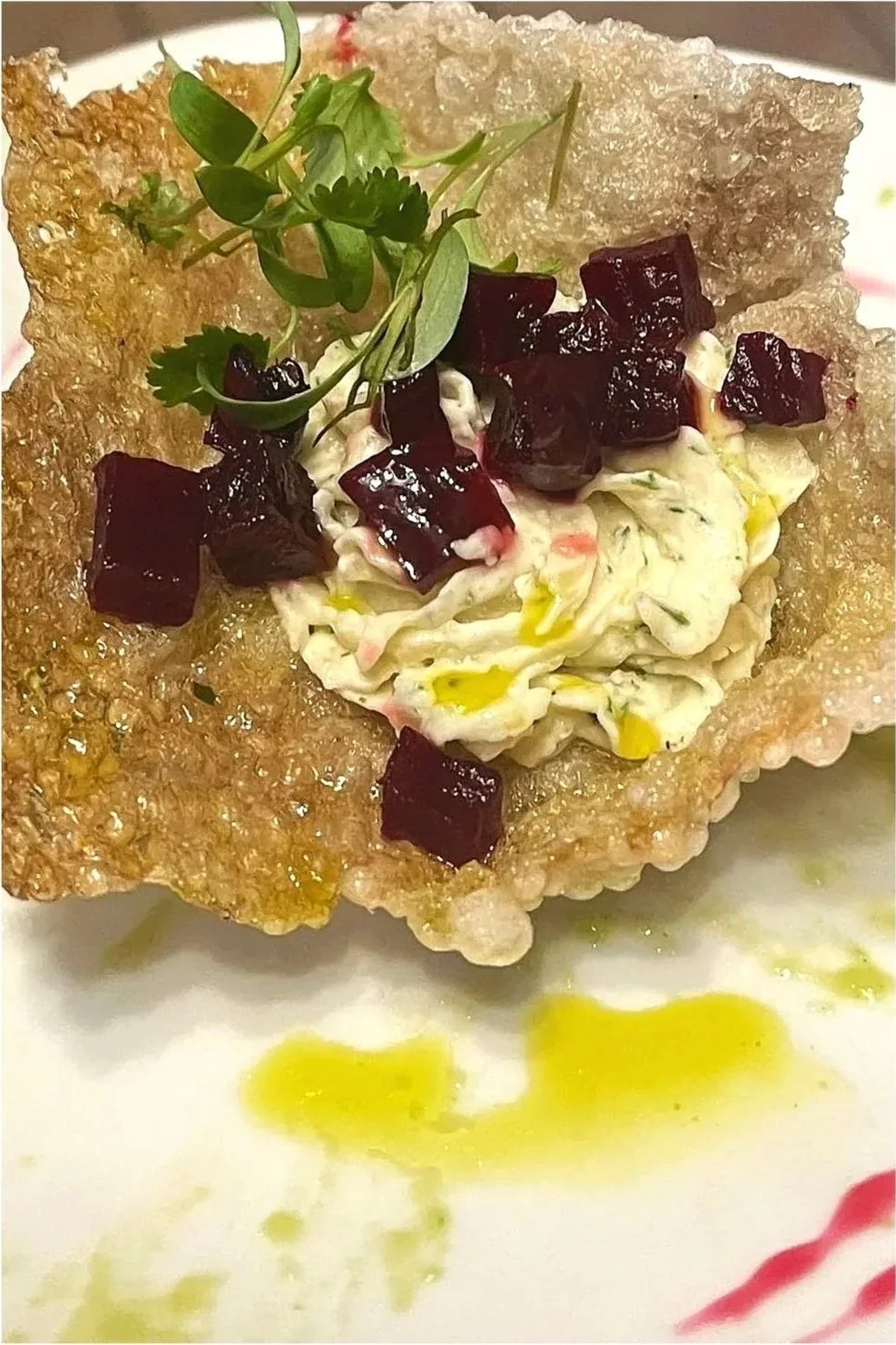 A crispy, fried edible bowl filled with a creamy salad topped with diced beets and a sprig of microgreens.