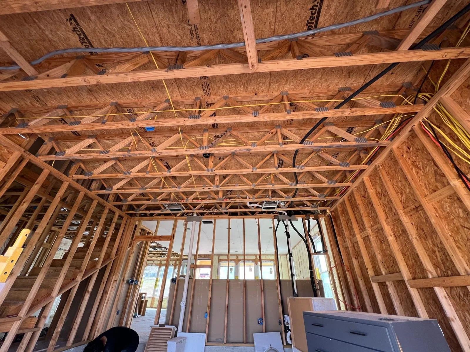 Interior view of a building under construction showing exposed wooden framing, electrical wiring, and unfinished walls.