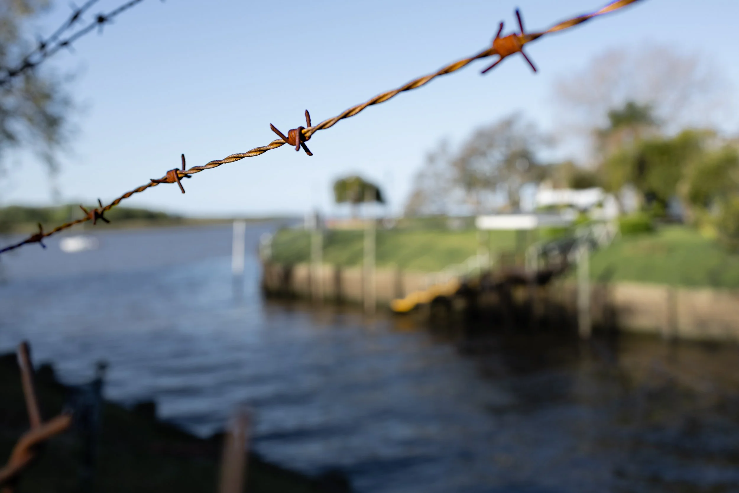 Red rusty fence next to a river