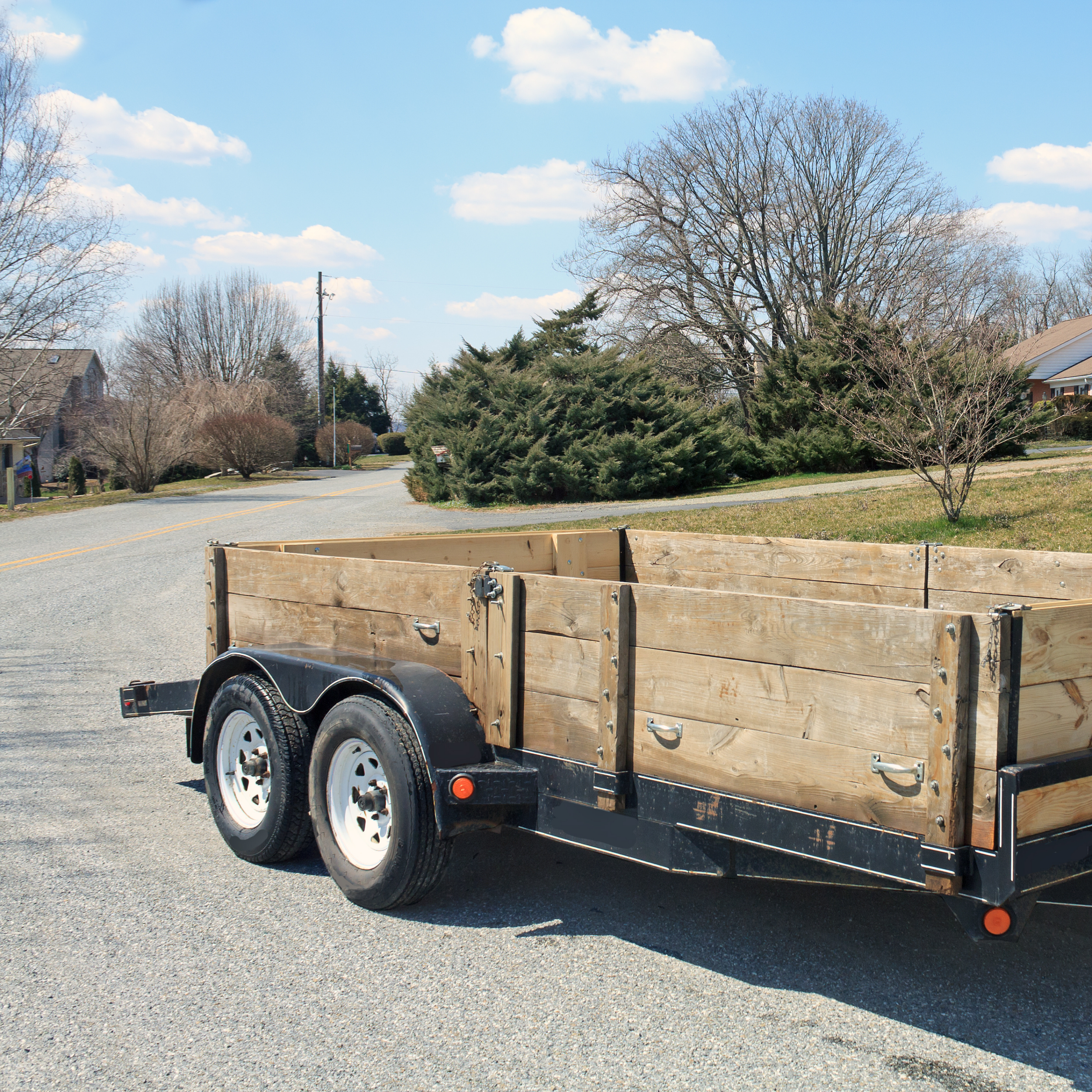An empty utility trailer parked on a residential street, representing junk removal services used when items are ready to be removed.