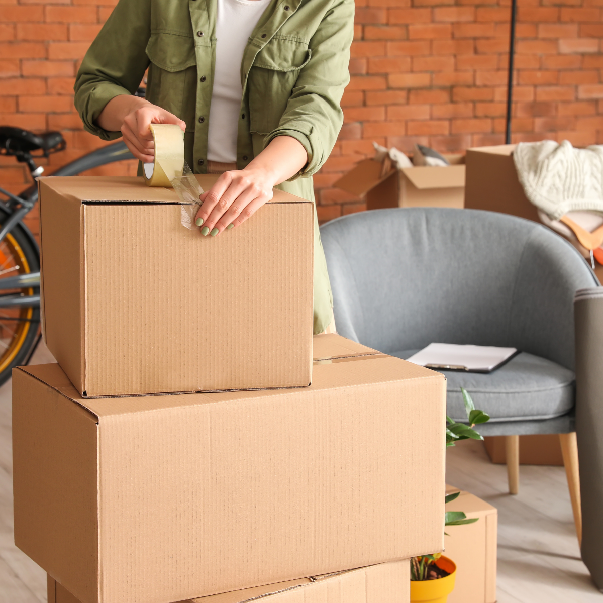 Hands packing household items into cardboard boxes, representing practical support during a home transition or estate-related move.