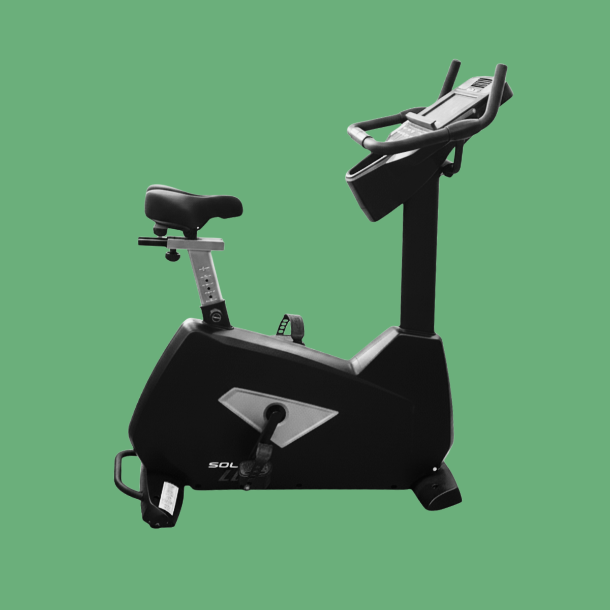 Black stationary exercise bike with digital display against a green background.