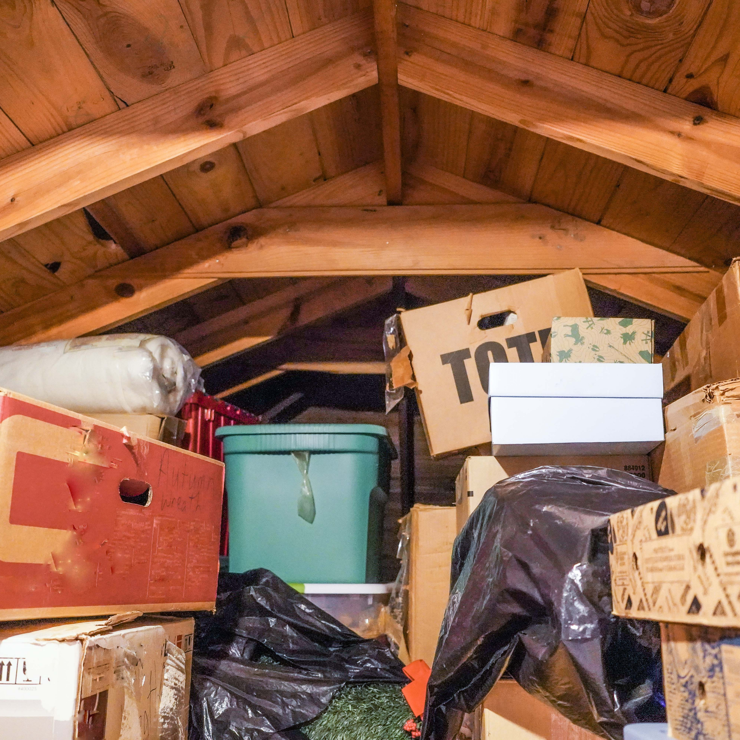 A cluttered attic space filled with stored boxes and household items, representing large-scale or hoarding-related cleanout situations.