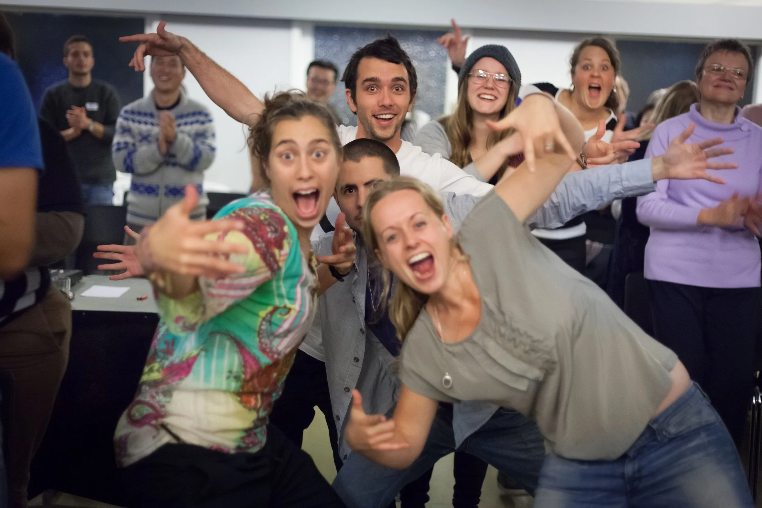 Group of people excited and celebrating at an indoor event or gathering.