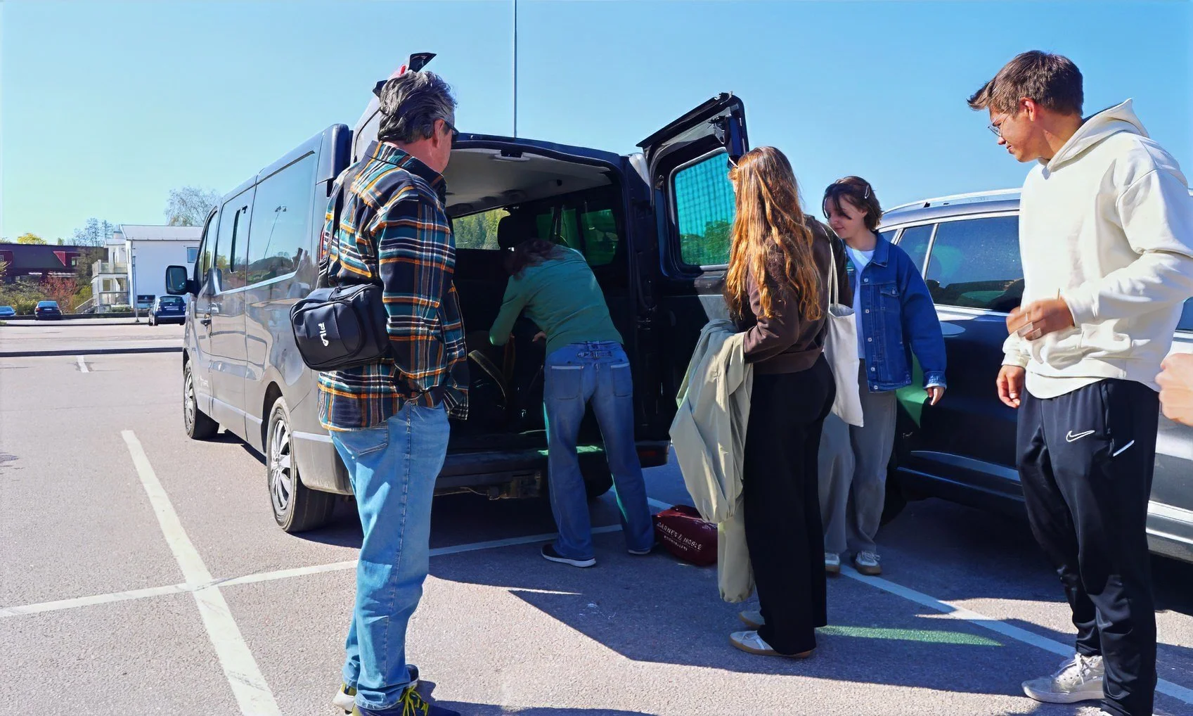 People put luggage into the back of a van
